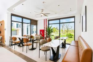 a restaurant with tables and chairs and large windows at The Muse Hotel 1 in Ðố Sơn