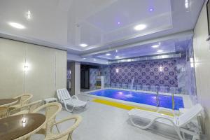 a swimming pool in a room with tables and chairs at Boutique Hotel IMONA in Samarkand