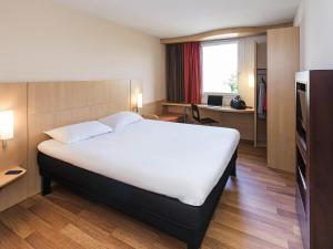 a hotel room with a large bed and a desk at ibis Montbéliard in Montbéliard