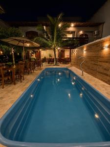 a large blue swimming pool at night with a restaurant at Flamingo Beach Pousada in Cabo Frio