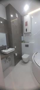 a white bathroom with a toilet and a sink at Hakim Karim Apartments in Khujand +2 photos