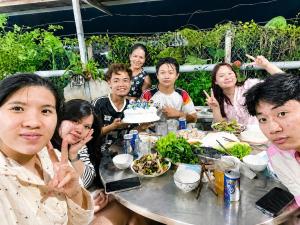 a group of people sitting at a table with a cake at Cali Homestay Tây Ninh in Tây Ninh