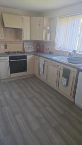 a kitchen with white cabinets and a black oven at Hilcot House in Kirby Muxloe