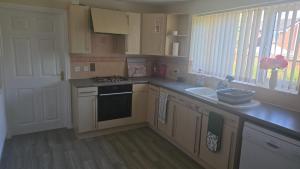 a kitchen with a sink and a stove top oven at Hilcot House in Kirby Muxloe