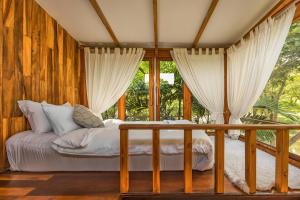 a bedroom with a bed in a room with windows at บ้านนาก๋างโต้ง Baan Na Kang Tong in Ban Kot