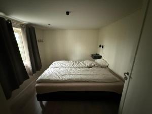 a small white bedroom with a bed and a window at Sjøveien 43 in Vestvågøya