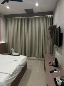 a hotel room with a bed and a desk with a television at King Residency in Chennai