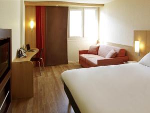 a hotel room with a bed and a couch at Ibis Roanne Le Coteau Hotel Restaurant in Le Coteau