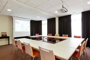 a conference room with tables and chairs and a projection screen at ibis Aulnay Paris Nord Expo in Aulnay-sous-Bois