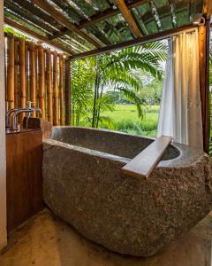 a large stone tub sitting in front of a window at บ้านนาก๋างโต้ง Baan Na Kang Tong in Ban Kot