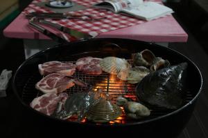 a grill with meat and seafood on top of it at Daecheon jeulgeoun pension in Boryeong
