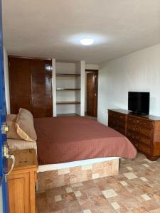 a bedroom with a bed and a dresser with a television at Hotel Casa Don Marcos in Ixtafiayuca