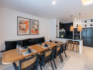 a dining room with a large wooden table and chairs at Kiara Beachtown Nusa Dua in Nusa Dua