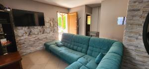 a blue couch in a living room with a flat screen tv at La Résidence de Lorelei in Cierp