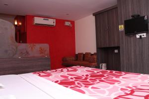 a hotel room with a bed and a flat screen tv at Hotel Shoven in Dāvangere