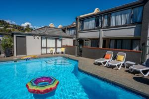 a swimming pool with chairs and a house at The Beachcomber Hotel in Nelson