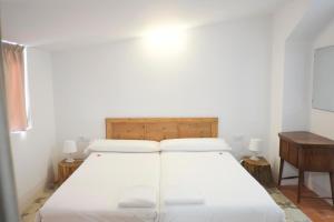 ein weißes Bett in einem Zimmer mit einem Kopfteil aus Holz in der Unterkunft Pigal in Tarragona