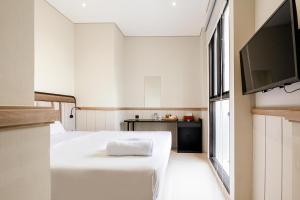 a room with a bed and a flat screen tv at Rucio Kostel Semarang in Jatingaleh