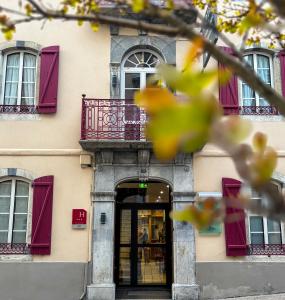 a building with red shuttered windows and a door at Hôtel La Montagne Fleurie in Barèges