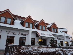 a building with snow on the roof at Hotel Zum Anger in Neukirchen-Pleiße