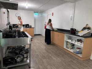 two women standing in a kitchen preparing food at Pippies Beachhouse Backpackers in Rainbow Beach +21 photos