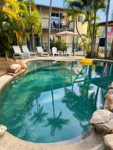 a large swimming pool with palm trees in a resort at Pippies Beachhouse Backpackers in Rainbow Beach