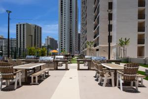 a patio with tables and chairs in a city at Waikiki condo - ocean views, lanai & beach access in Honolulu
