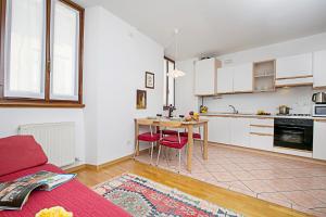 a kitchen with white cabinets and a table with red chairs at Appartamento Centro Storico Riva 2 - Happy Rentals in Riva del Garda