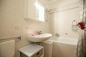 a white bathroom with a sink and a bath tub at Appartamento Centro Storico Riva 2 - Happy Rentals in Riva del Garda