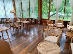 a room with wooden tables and chairs and windows at บ้านนาก๋างโต้ง Baan Na Kang Tong in Ban Kot
