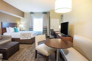 a hotel room with a bed and a desk with a television at Hawthorn Suites by Wyndham Saint Clairsville in Saint Clairsville