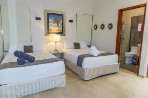 two beds in a hotel room with a bathroom at Hotel Scarlette in Tulum +33 photos