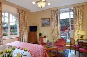 a bedroom with a bed and chairs and windows at Hostellerie de la Motte jean in Saint-Coulomb