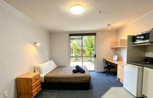 a bedroom with a bed and a desk and a kitchen at Cube Lite Apartments in Hamilton