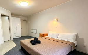 a bedroom with a bed with a black bag on it at Cube Lite Apartments in Hamilton