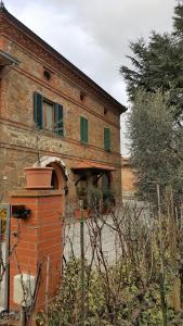 un antiguo edificio de ladrillo con una ventana y una valla en Orto degli Ulivi, en Sinalunga