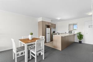 a kitchen and dining room with a table and chairs at Direct Collective - Breeze on Brightwater in Mooloolaba