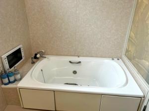 a white bath tub in a bathroom with a tv at LCO-Resort in Takizawa +30 photos