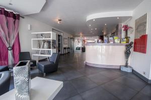 a salon with a counter and chairs in a room at Citotel Hôtel Le Capricorne in Marmande