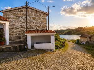 a stone building on a cobblestone road next to a lake at Casa D'os Eiras in Aguiar da Beira +12 photos