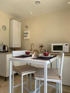 a kitchen with a white table with chairs and a microwave at La CléryNette in Les Andelys