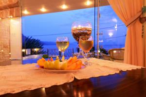 two glasses of wine and a plate of fruit on a table at Ilia Mare in Ilia