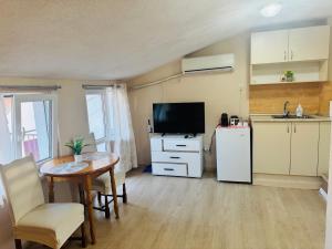 a living room with a table and a kitchen with a television at Room Nencheva in Sandanski