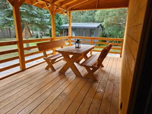 a wooden porch with a wooden table and benches at Odpoczynkowo in Orle