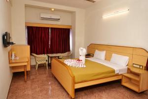 a bedroom with a bed and a desk and a window at Sakthi Hotel in Pollāchi +62 photos