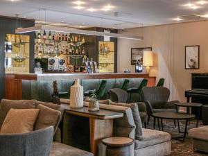 a bar with couches and chairs and a piano at Novotel Bayeux in Bayeux