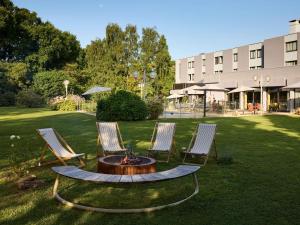 a group of three chairs and a fire pit in a yard at Novotel Bayeux in Bayeux