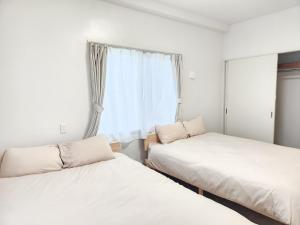 two beds in a room with a window at seragaki blue twins 201 in Onna