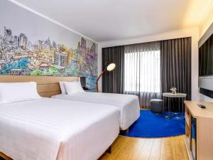 two beds in a hotel room with a mural on the wall at Novotel Bangkok on Siam Square in Bangkok