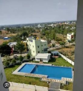arial view of a swimming pool in front of a building at Ra3sheesh Abode Comfort Connectivity and Charm in Dera Bassi